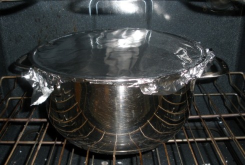 I covered it with foil because my Dutch oven has a glass lid with a gasket.  I don't trust that gasket in the oven.